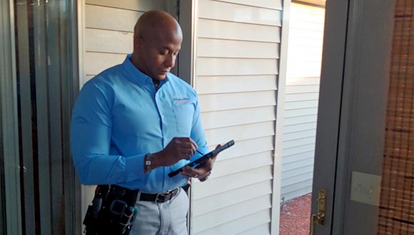 Carlos Sanchez Walker, professional home inspector, in front of a house, going over the checklist.